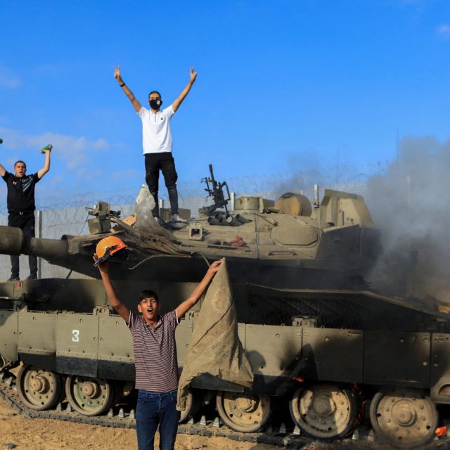 Palestinci oslavují hořící izraelské vojenské vozidlo zasažené palestinskými ozbrojenci,  kteří pronikli do oblastí jižního Izraele | foto: Reuters
